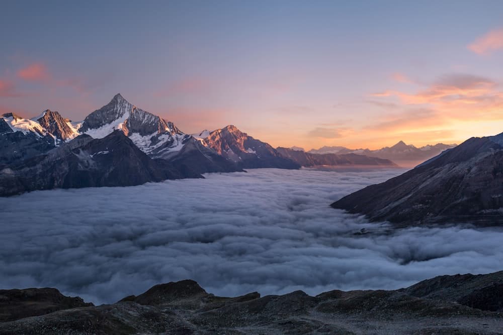Misty mountain peaks rising above the clouds at dawn